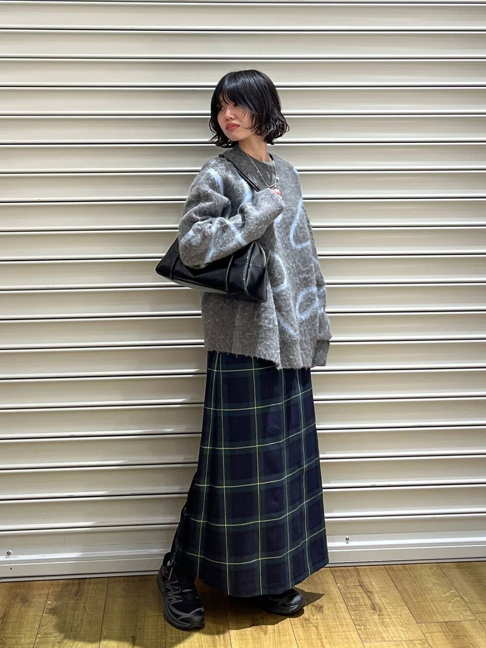 グリーン系のスカート、ブラック系のボストンバッグ、グレー系のニット/セーターを着用したレディースの冬コーディネートの3枚目の写真