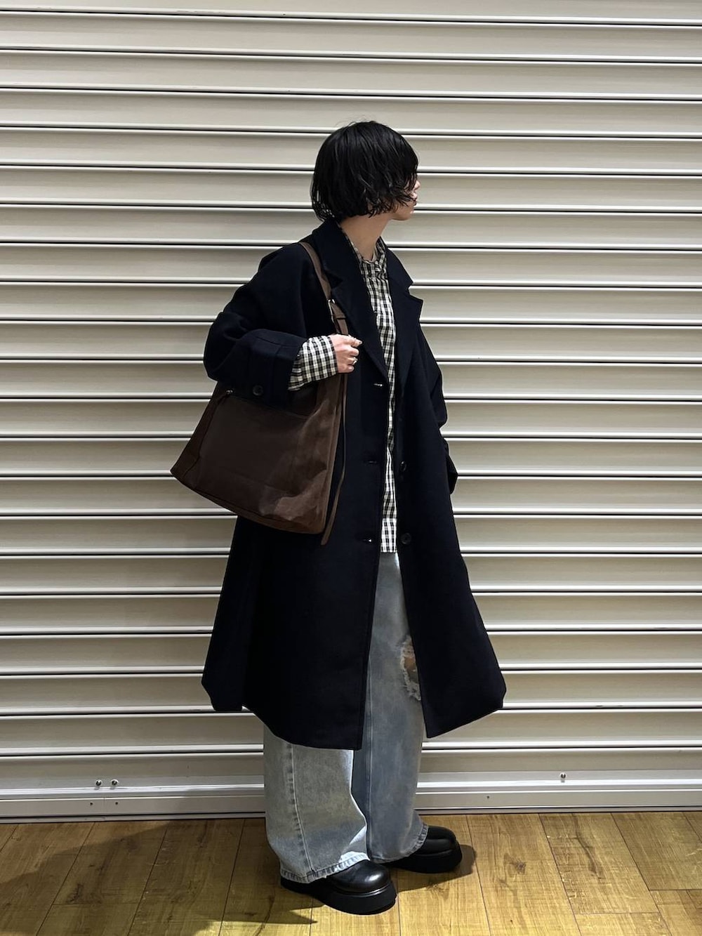 ブラウン系のショルダーバッグ、ブルー系のチェスターコート、ブラック系のサンダルを着用したレディースの冬コーディネートの2枚目の写真