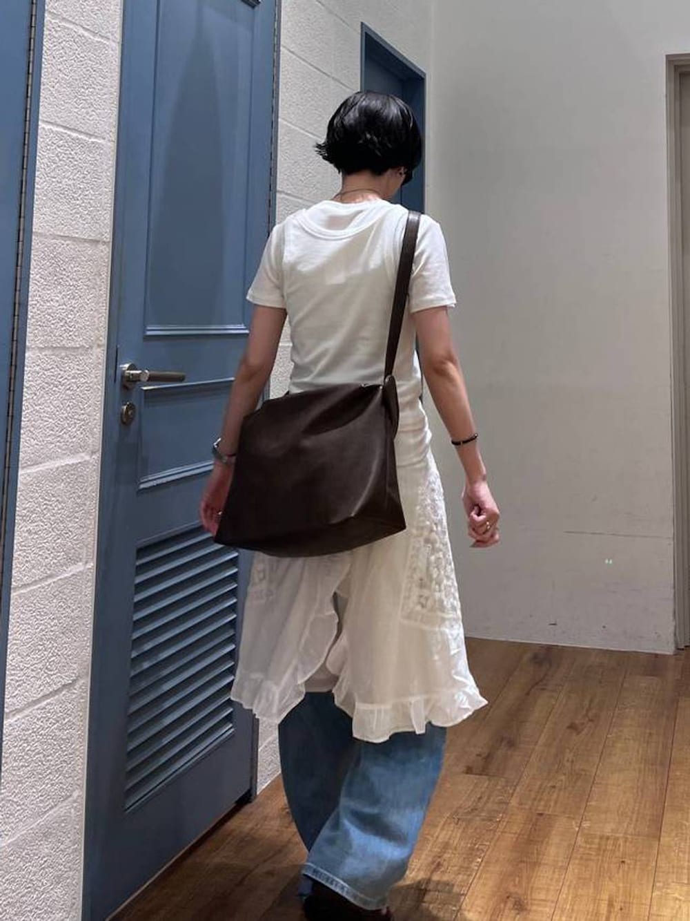ブラック系のショルダーバッグ、ホワイト系のTシャツ/カットソー、ブルー系のデニムパンツを着用したレディースの夏コーディネートの3枚目の写真