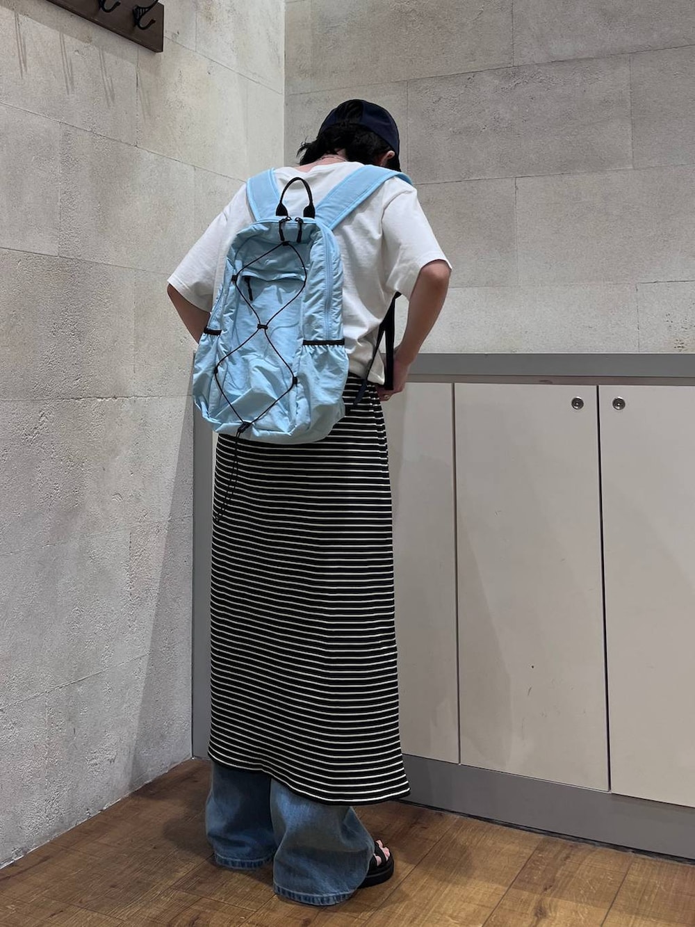 ブルー系のデニムパンツ、ブラック系のサンダル、ホワイト系のTシャツ/カットソーを着用したレディースの夏コーディネートの4枚目の写真