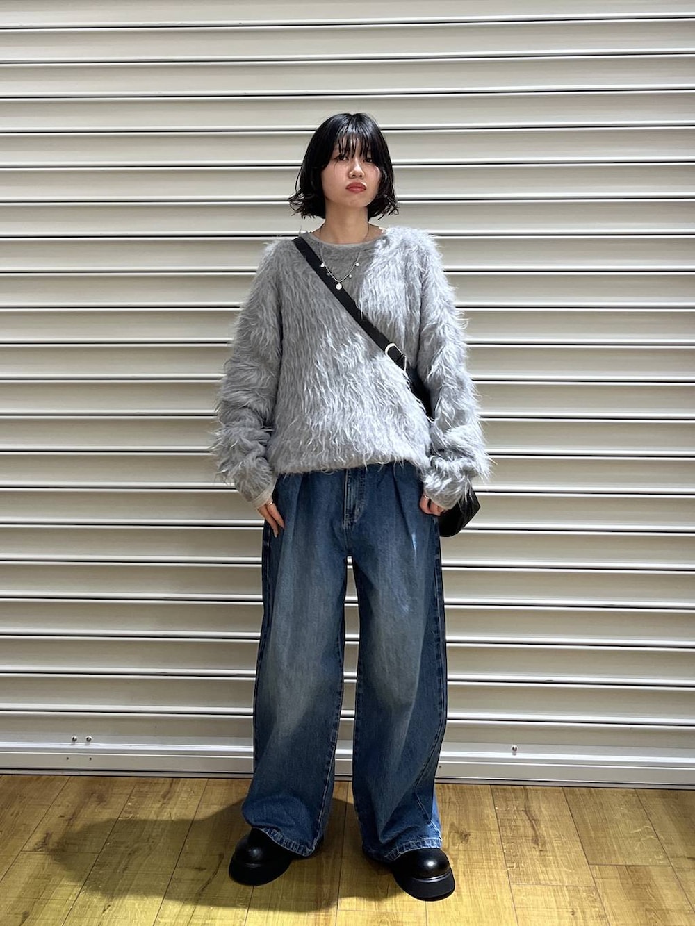 ブラック系のショルダーバッグ、ブラック系のサンダル、ブルー系のデニムパンツを着用したレディースの冬コーディネートの4枚目の写真