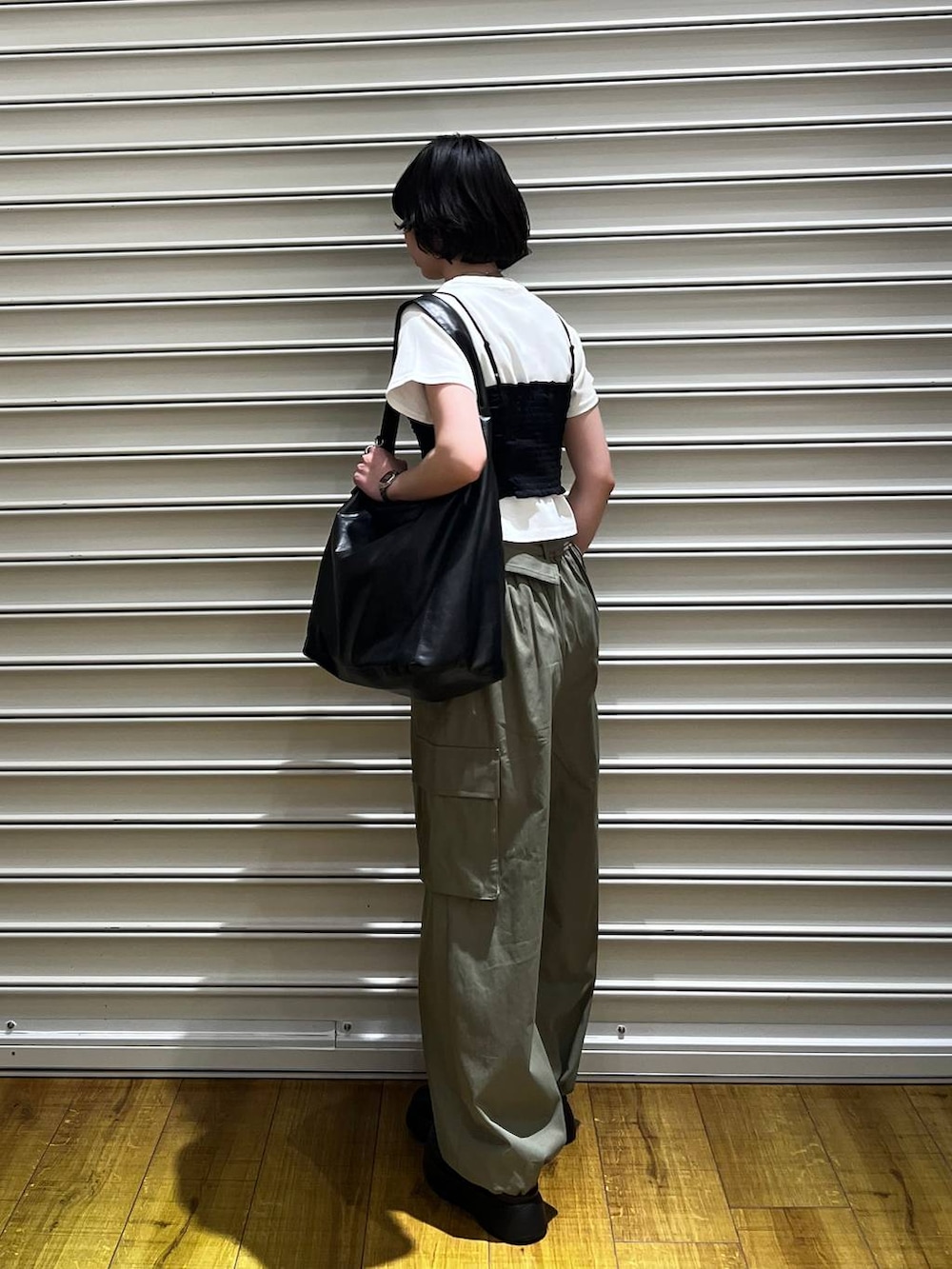 ブラック系のショルダーバッグ、ブラック系のサンダル、ホワイト系のTシャツ/カットソーを着用したレディースの春コーディネートの3枚目の写真