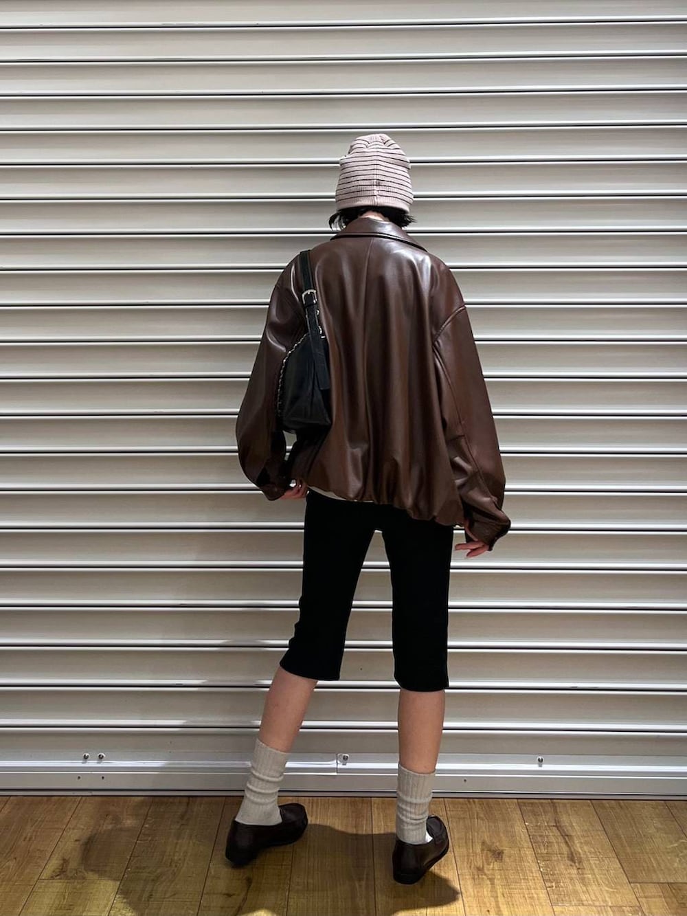 ブラック系のショルダーバッグ、ブラウン系のローファー、ホワイト系のベストを着用したレディースの春コーディネートの3枚目の写真