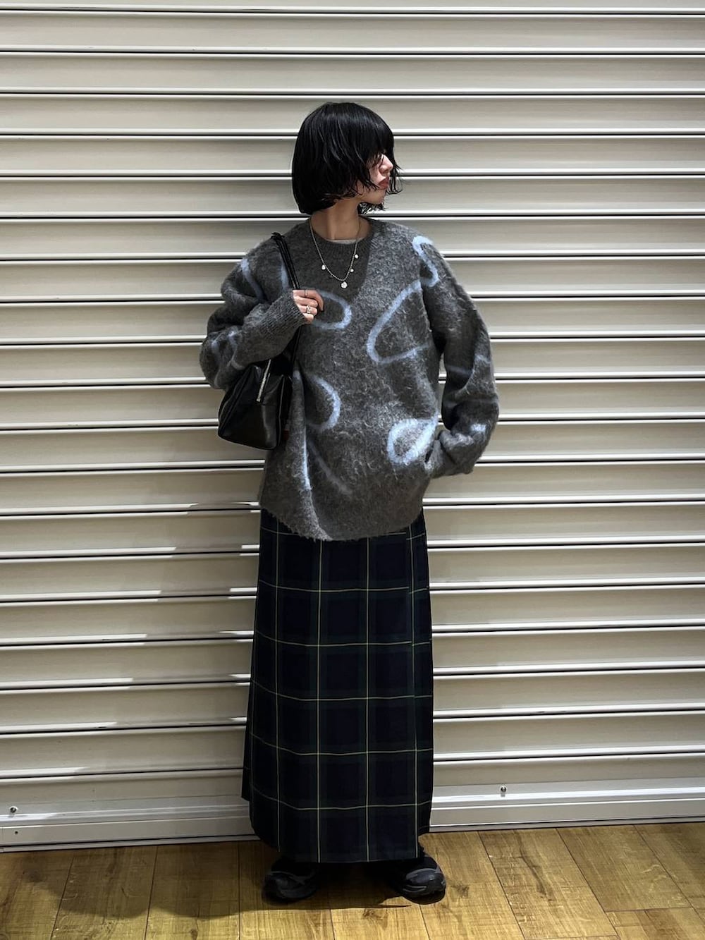 グリーン系のスカート、ブラック系のボストンバッグ、グレー系のニット/セーターを着用したレディースの冬コーディネートの2枚目の写真