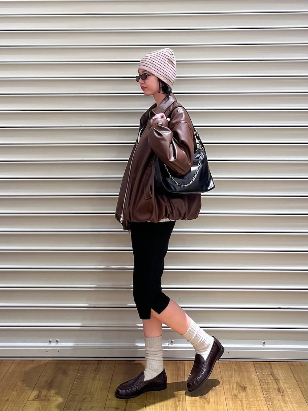 ブラック系のショルダーバッグ、ブラウン系のローファー、ホワイト系のベストを着用したレディースの春コーディネートの2枚目の写真