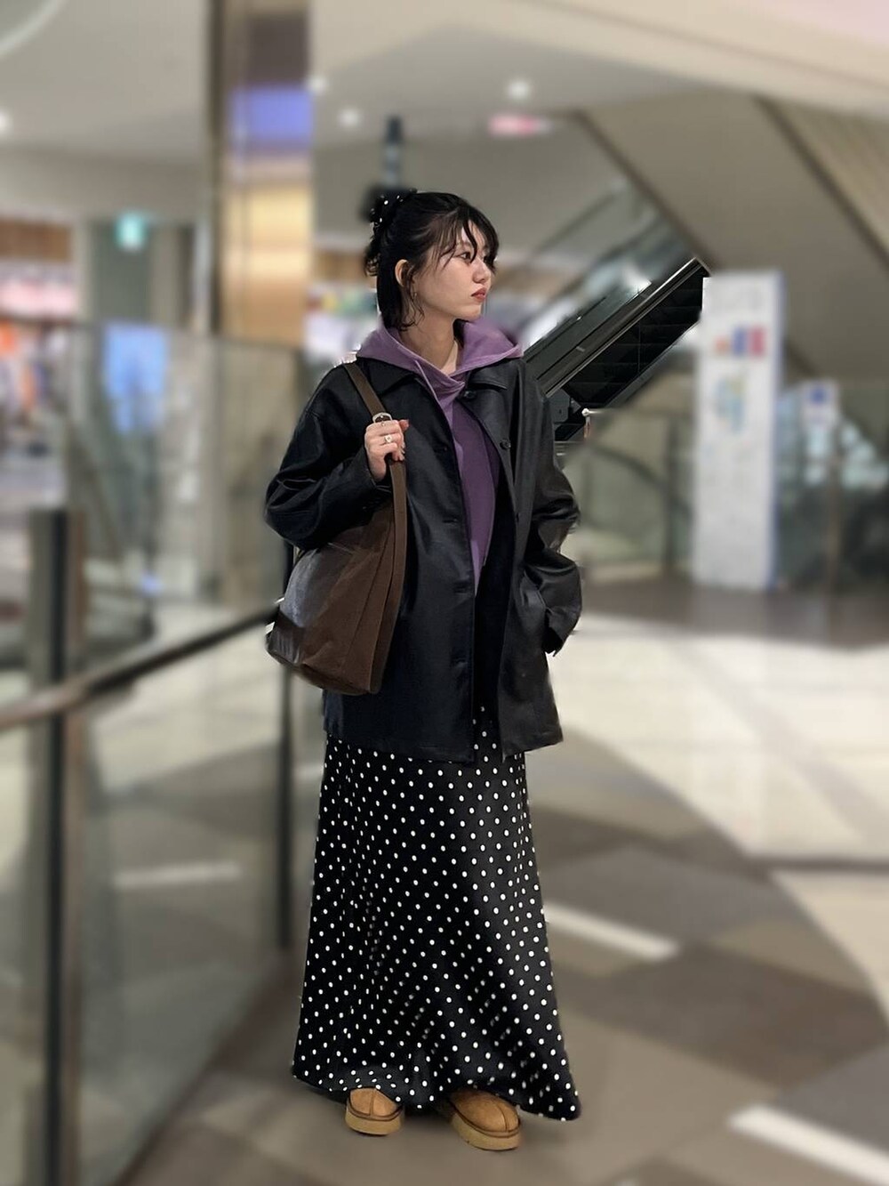 ブラウン系のショルダーバッグ、ブラック系のスカート、パープル系のパーカーを着用したレディースの秋コーディネートの2枚目の写真