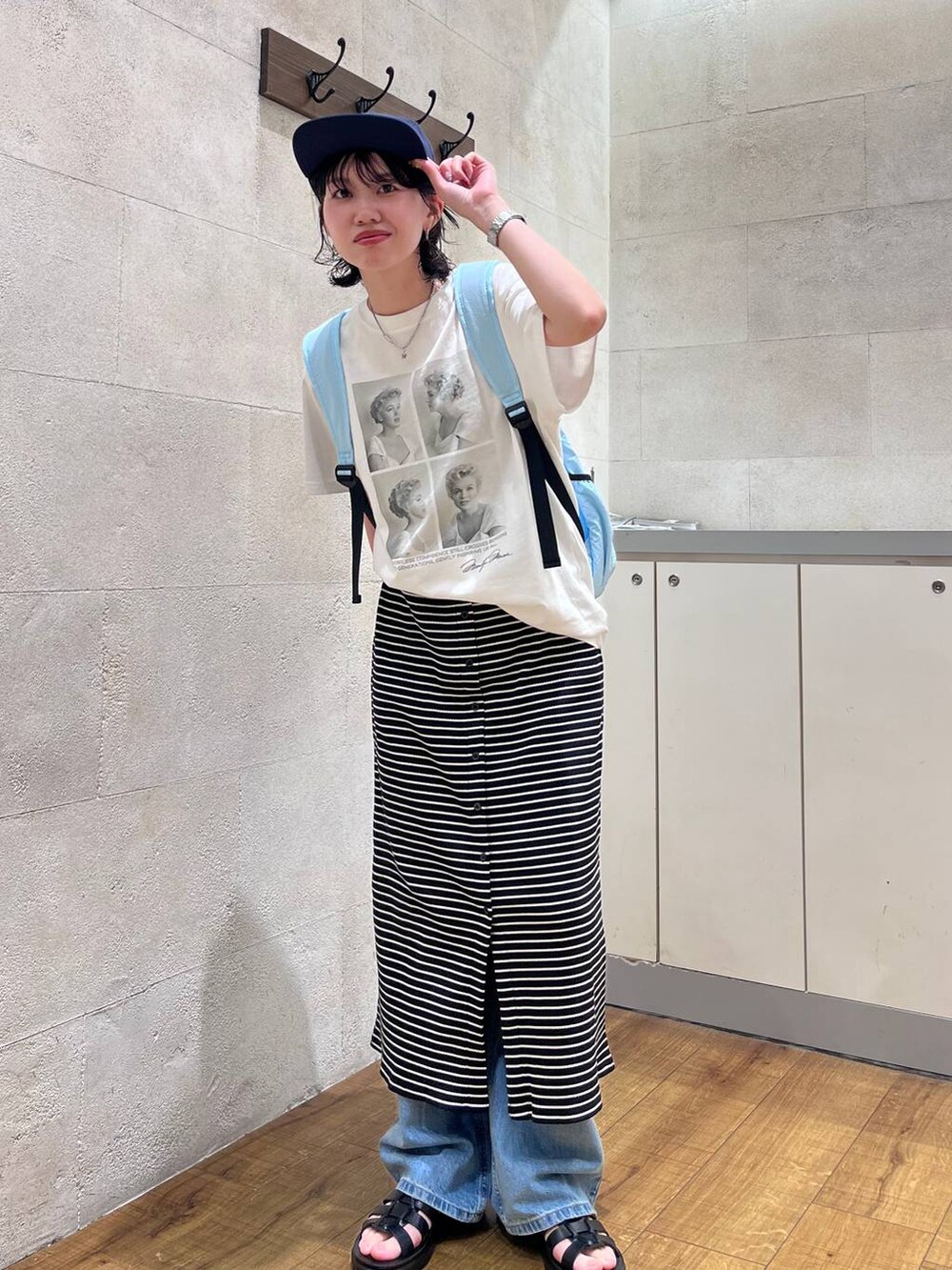 ブルー系のデニムパンツ、ブラック系のサンダル、ホワイト系のTシャツ/カットソーを着用したレディースの夏コーディネートの2枚目の写真