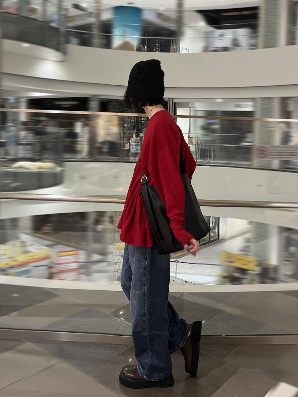 ブルー系のデニムパンツ、ブラウン系のサンダル、ブラック系のショルダーバッグを着用したレディースの秋コーディネートの2枚目の写真