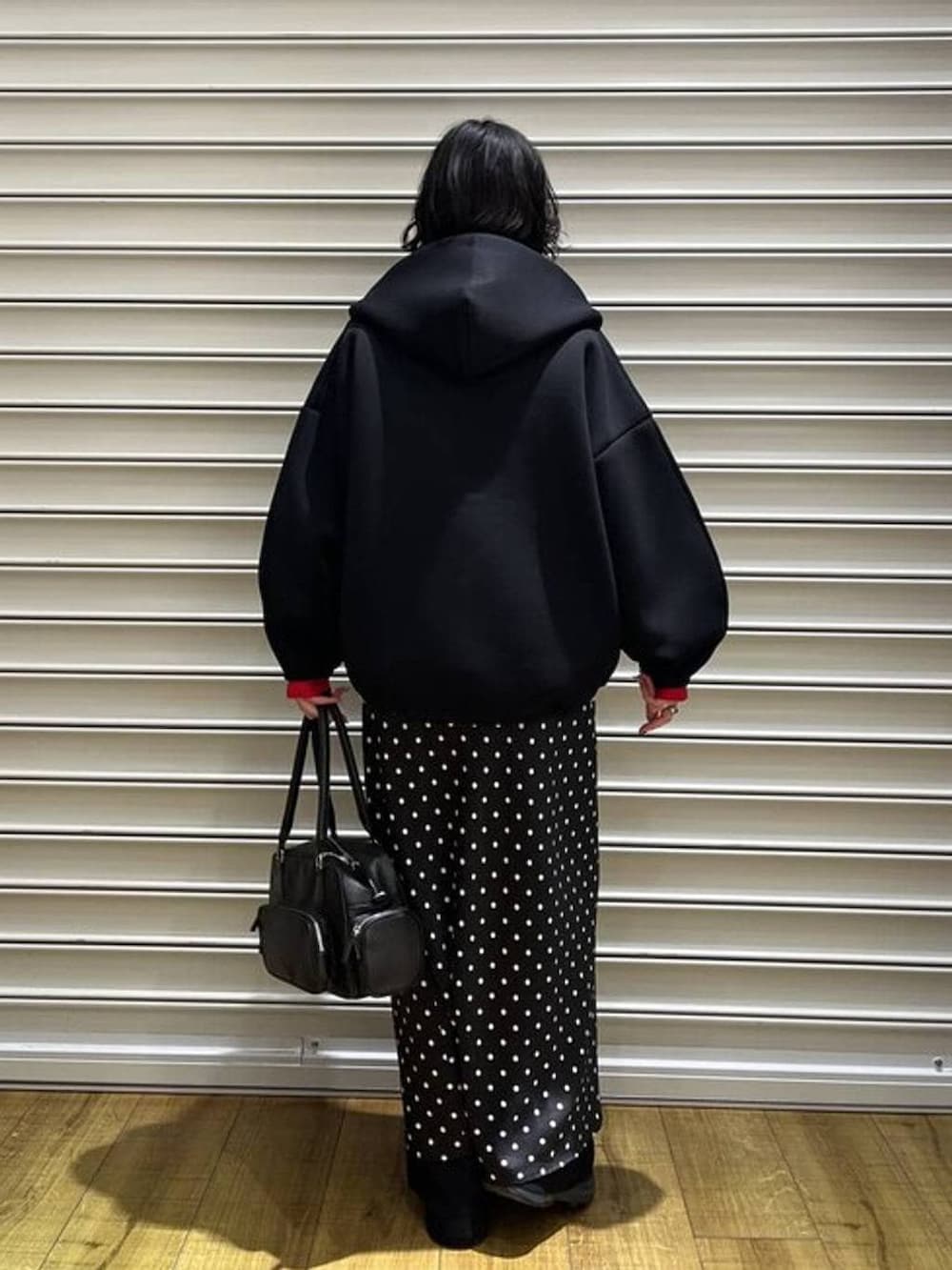 ブラック系のスカート、レッド系のニット/セーター、ブラック系のその他パンツを着用したレディースの冬コーディネートの3枚目の写真