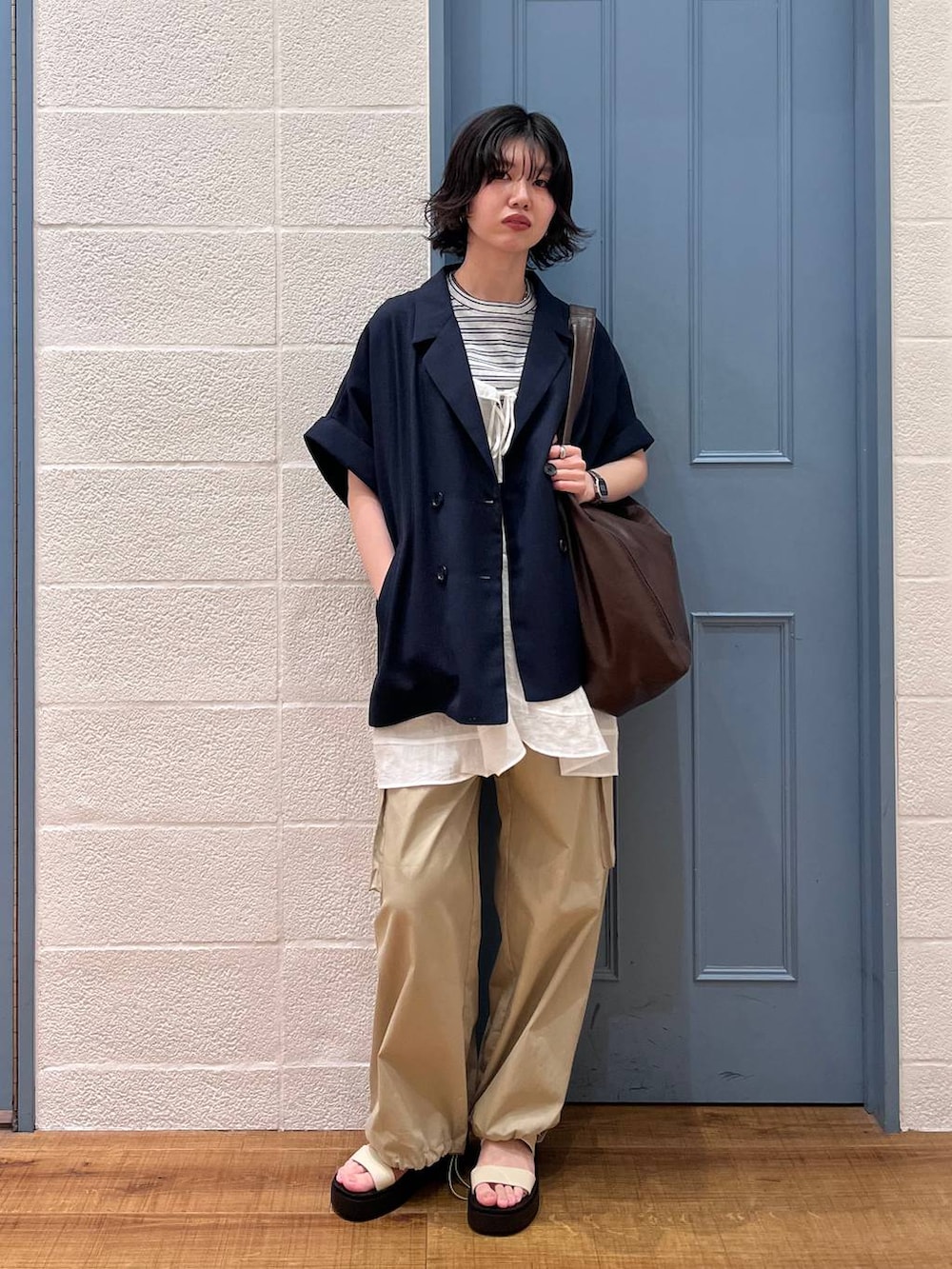 ブラウン系のショルダーバッグ、グレー系のTシャツ/カットソー、ブルー系のテーラードジャケットを着用したレディースの春コーディネートの3枚目の写真
