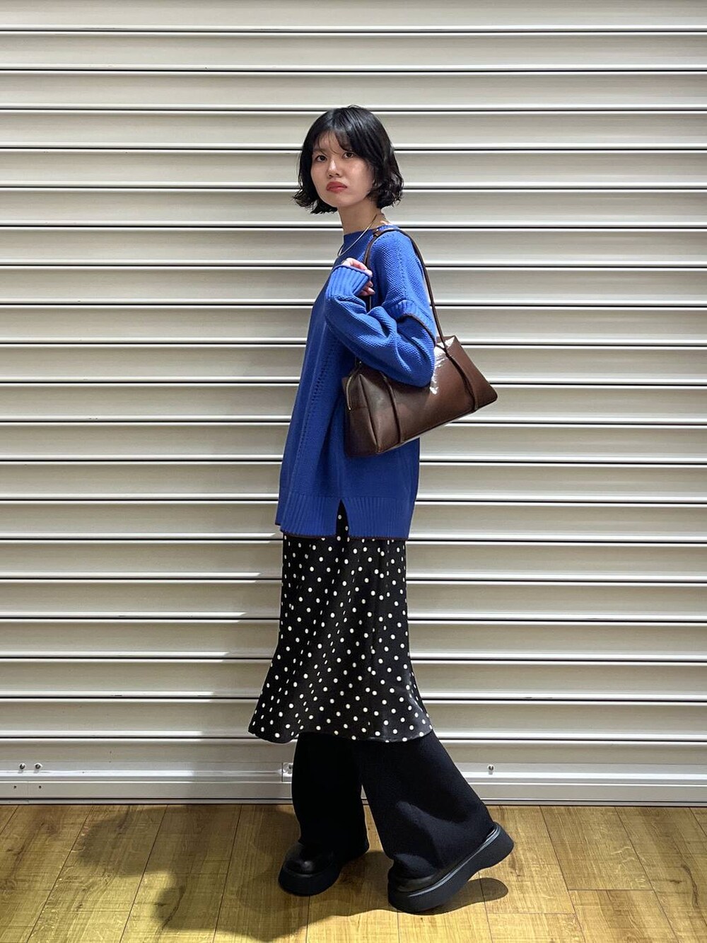 ブラック系のスカート、ブルー系のニット/セーター、ブラック系のサンダルを着用したレディースの秋コーディネートの2枚目の写真