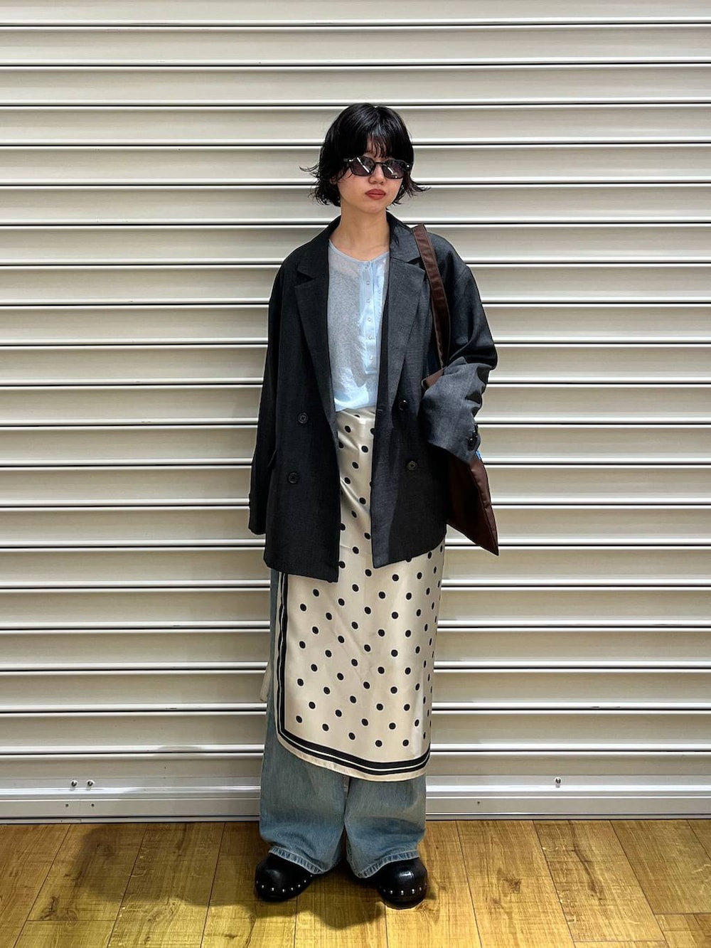 グレー系のテーラードジャケット、ブルー系のデニムパンツ、ブラック系のサンダルを着用したレディースの春コーディネートの2枚目の写真