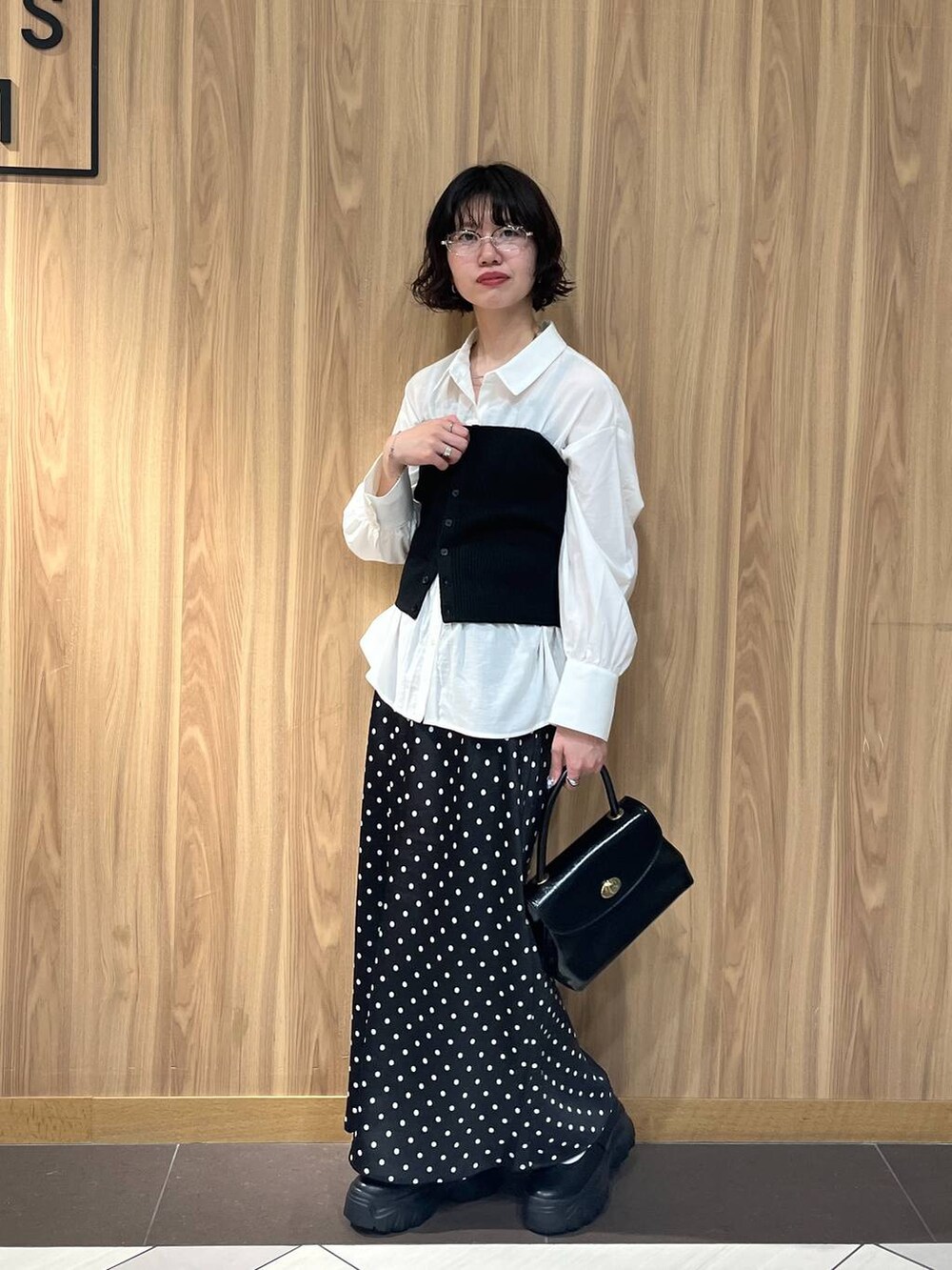 ブラック系のスニーカー、ブラック系のスカート、ブラック系のボストンバッグを着用したレディースの秋コーディネートの4枚目の写真