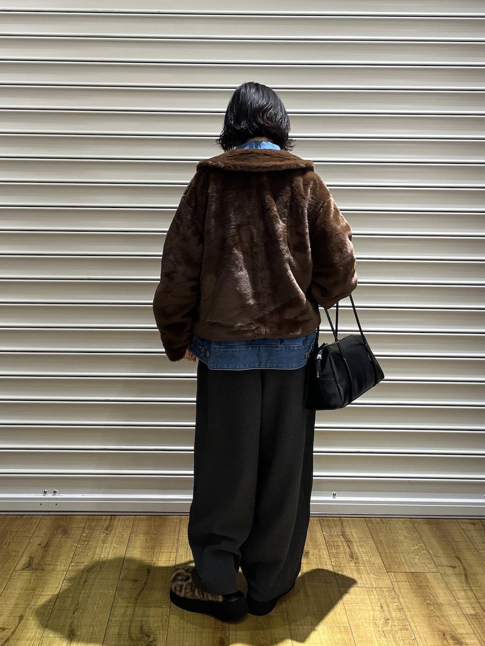 ブラウン系のブルゾン、ブルー系のデニムジャケット、ブラック系のボストンバッグを着用したレディースの秋コーディネートの3枚目の写真