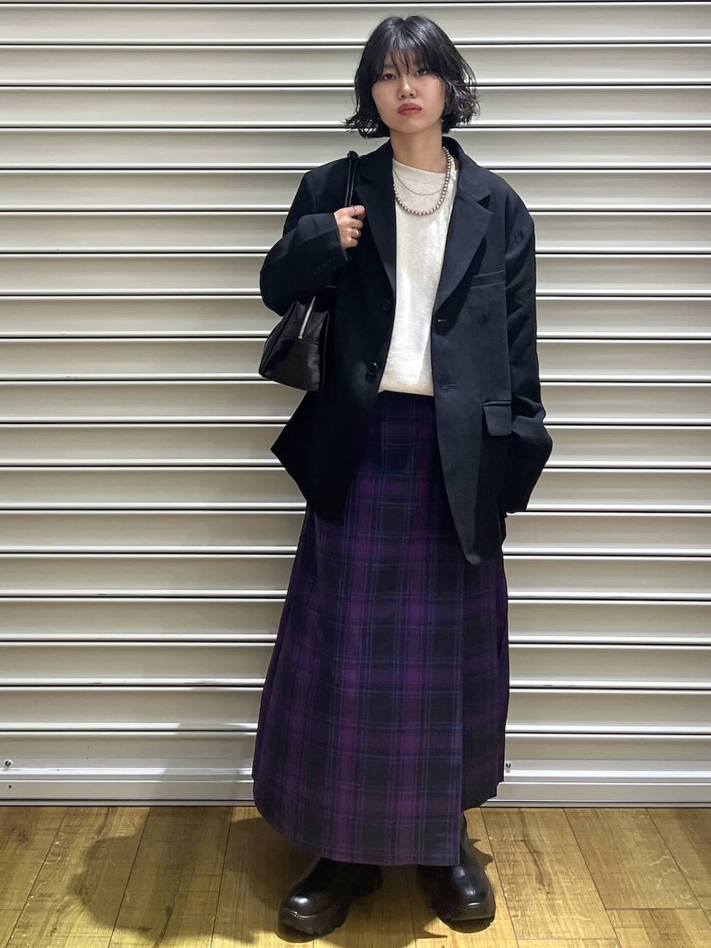 ブラック系のブーツ、ブラック系のテーラードジャケット、パープル系のスカートを着用したレディースの冬コーディネートの2枚目の写真