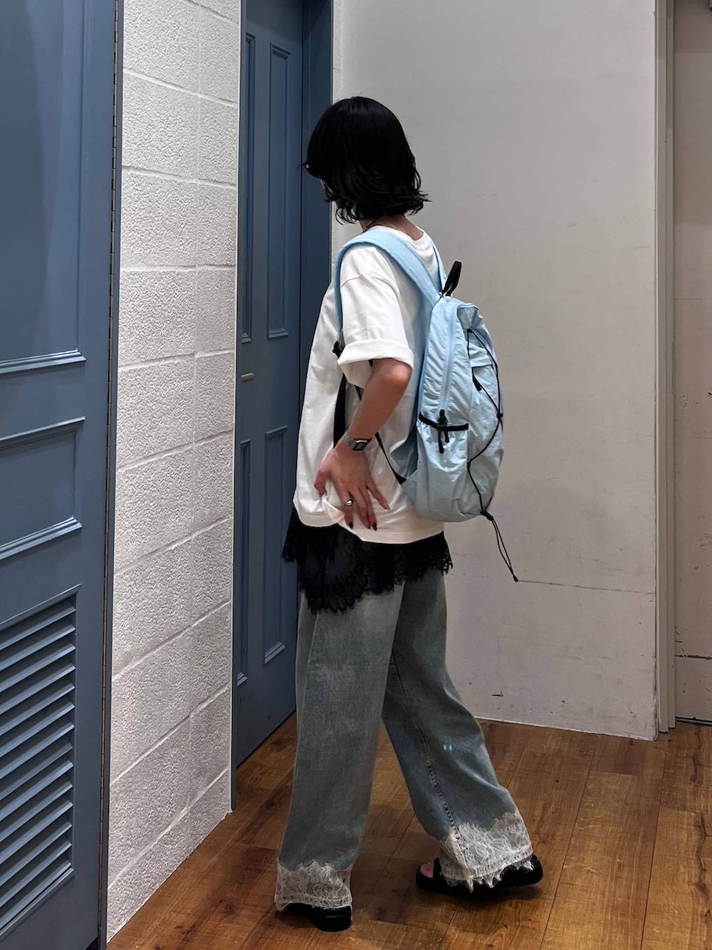 ブルー系のデニムパンツ、ブラック系のサンダル、ブラック系のTシャツ/カットソーを着用したレディースの夏コーディネートの3枚目の写真