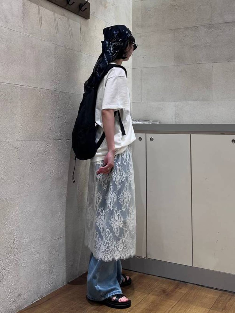 ブルー系のデニムパンツ、ブラック系のサンダル、ホワイト系のTシャツ/カットソーを着用したレディースの夏コーディネートの3枚目の写真