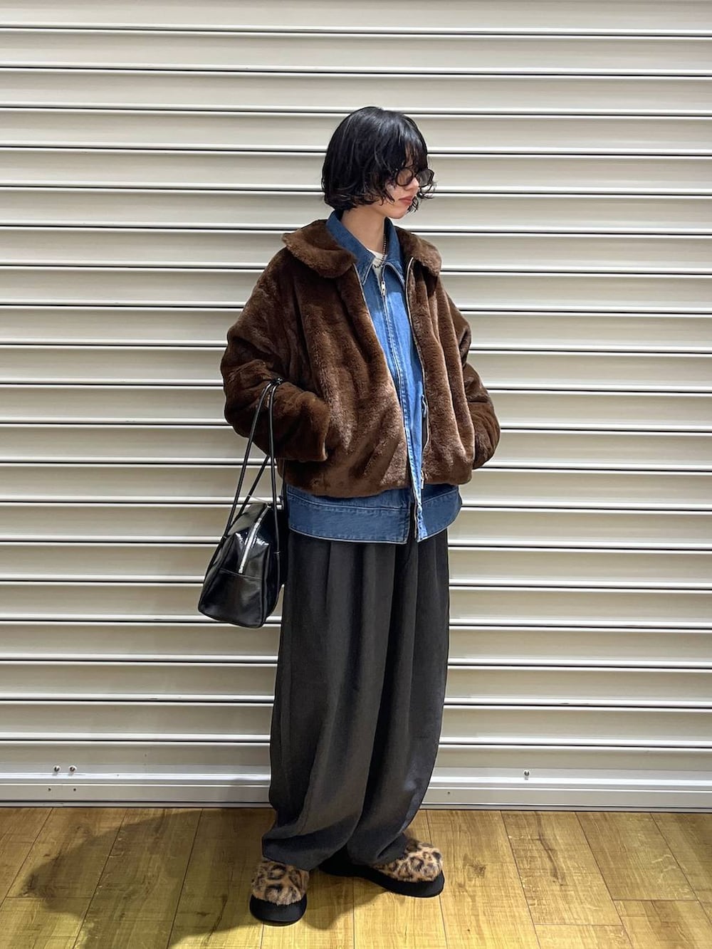 ブラウン系のブルゾン、ブルー系のデニムジャケット、ブラック系のボストンバッグを着用したレディースの秋コーディネートの4枚目の写真