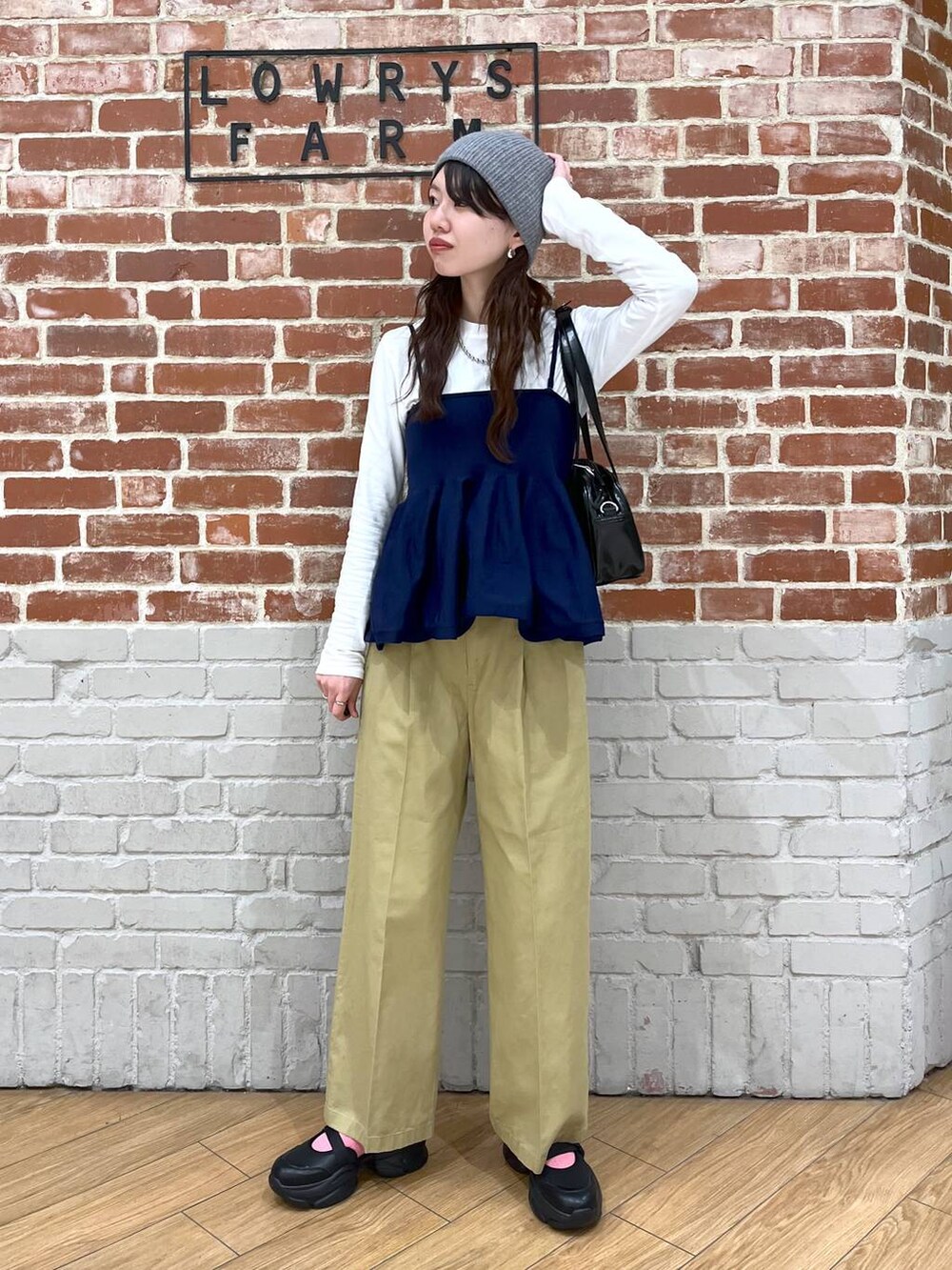 ブラック系のハンドバッグ、ブラック系のサンダル、ホワイト系のTシャツ/カットソーを着用したレディースの春コーディネートの2枚目の写真