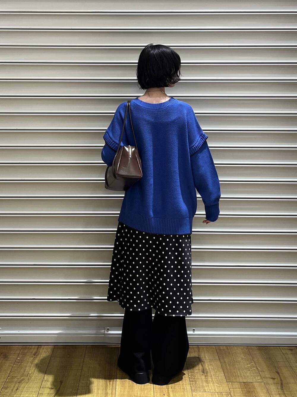 ブラック系のスカート、ブルー系のニット/セーター、ブラック系のサンダルを着用したレディースの秋コーディネートの3枚目の写真