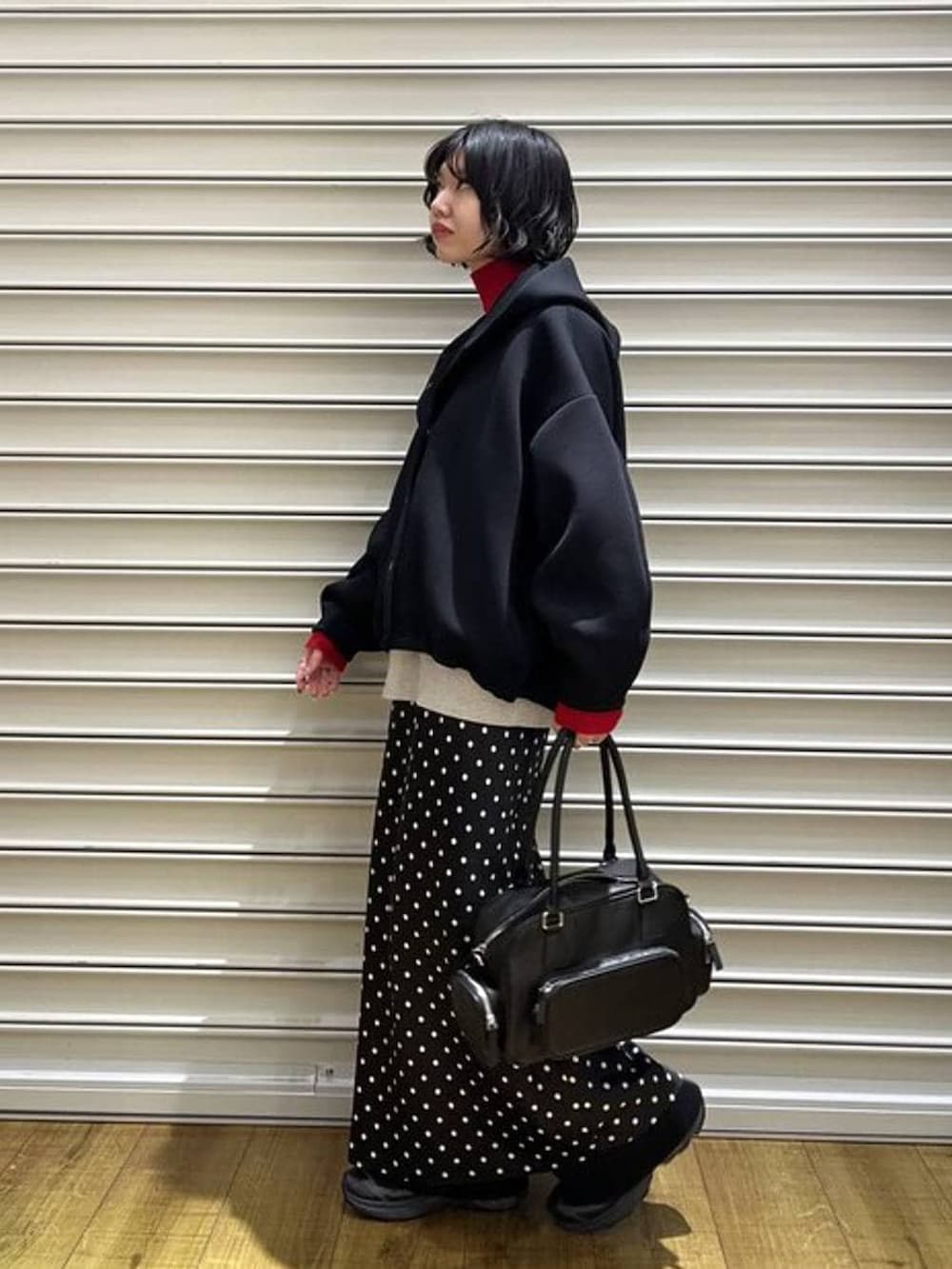 ブラック系のスカート、レッド系のニット/セーター、ブラック系のその他パンツを着用したレディースの冬コーディネートの2枚目の写真