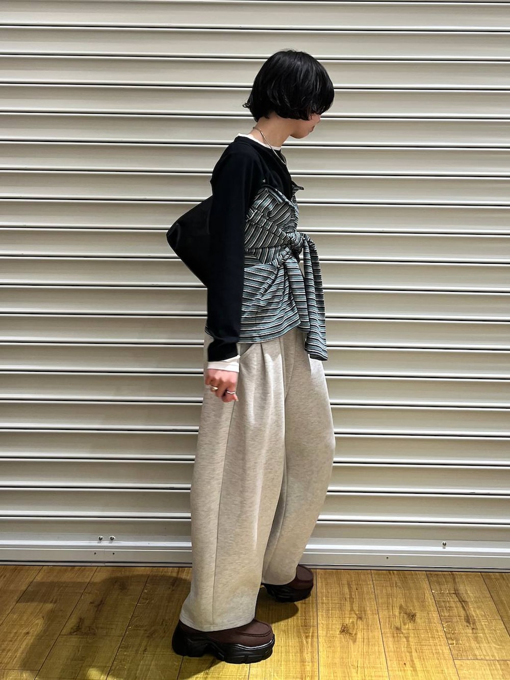 グレー系のスウェットパンツ、ブラウン系のローファー、グリーン系のカーディガン/ボレロを着用したレディースの春コーディネートの2枚目の写真