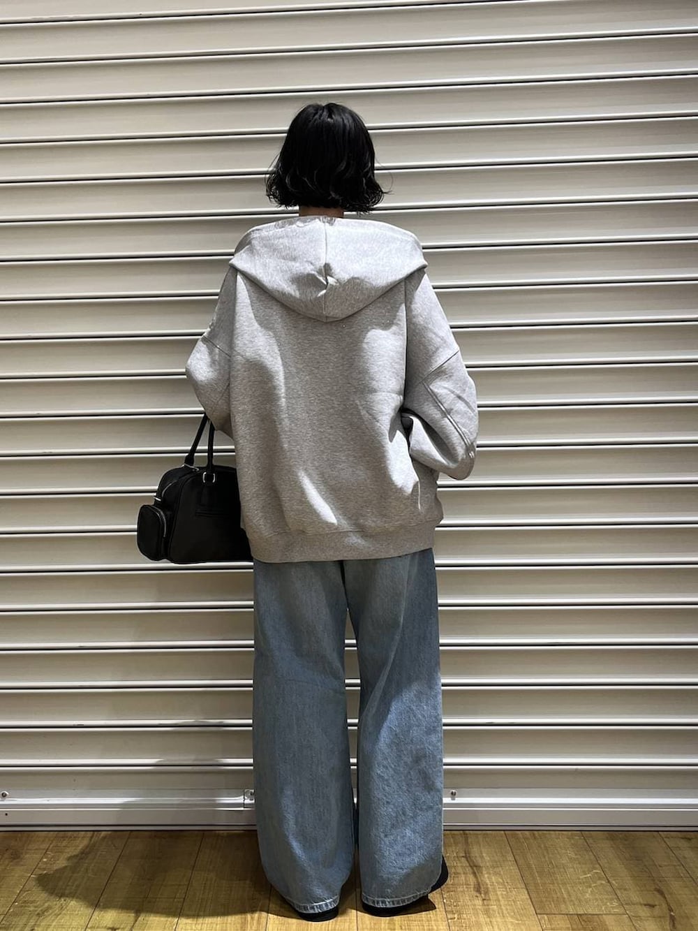 グレー系のパーカー、ブルー系のデニムパンツ、ブラック系のボストンバッグを着用したレディースの冬コーディネートの3枚目の写真