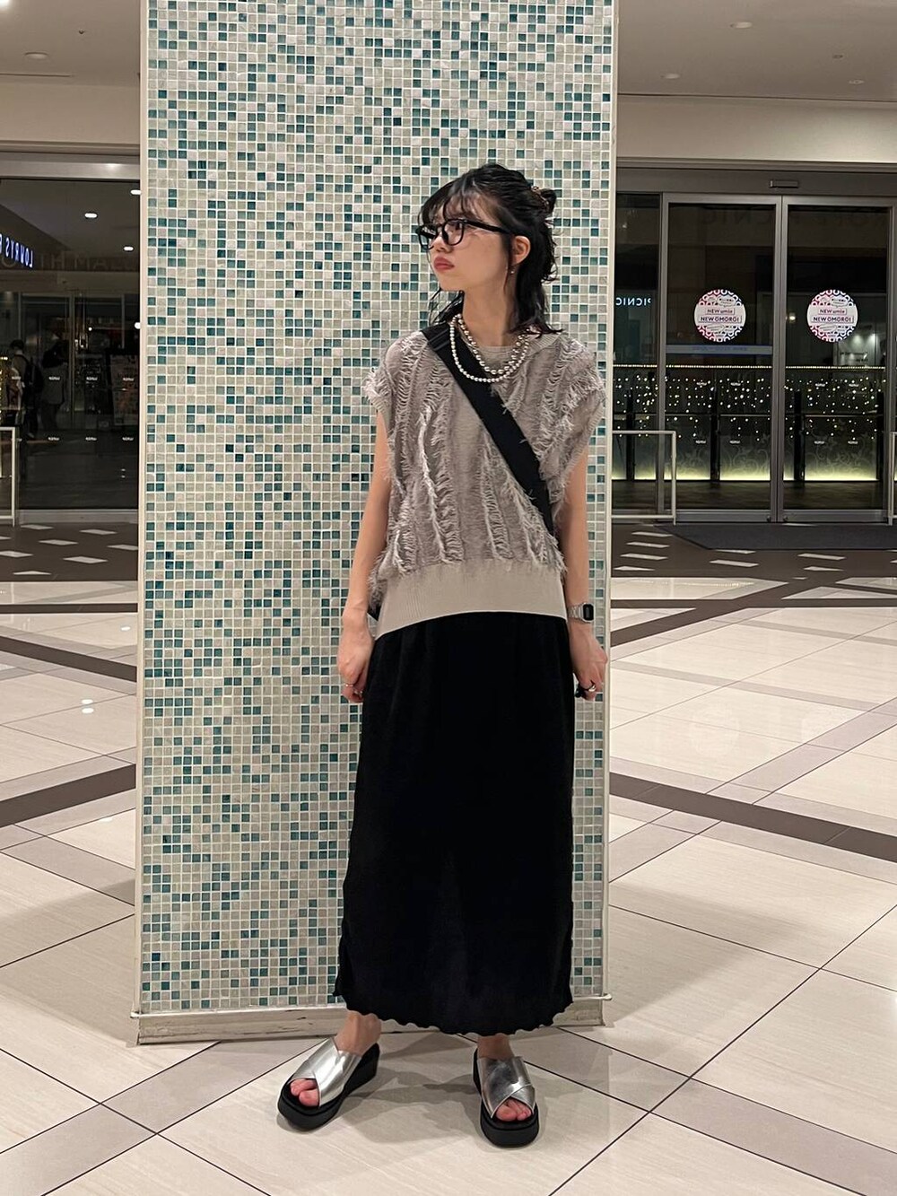 シルバー系のサンダル、ブラック系のショルダーバッグ、ブラック系のスカートを着用したレディースの夏コーディネートの2枚目の写真