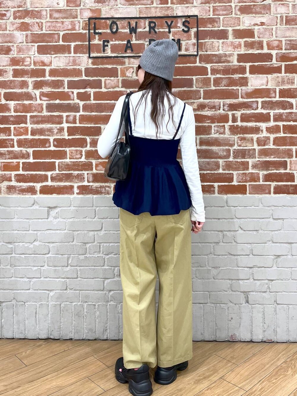 ブラック系のハンドバッグ、ブラック系のサンダル、ホワイト系のTシャツ/カットソーを着用したレディースの春コーディネートの3枚目の写真