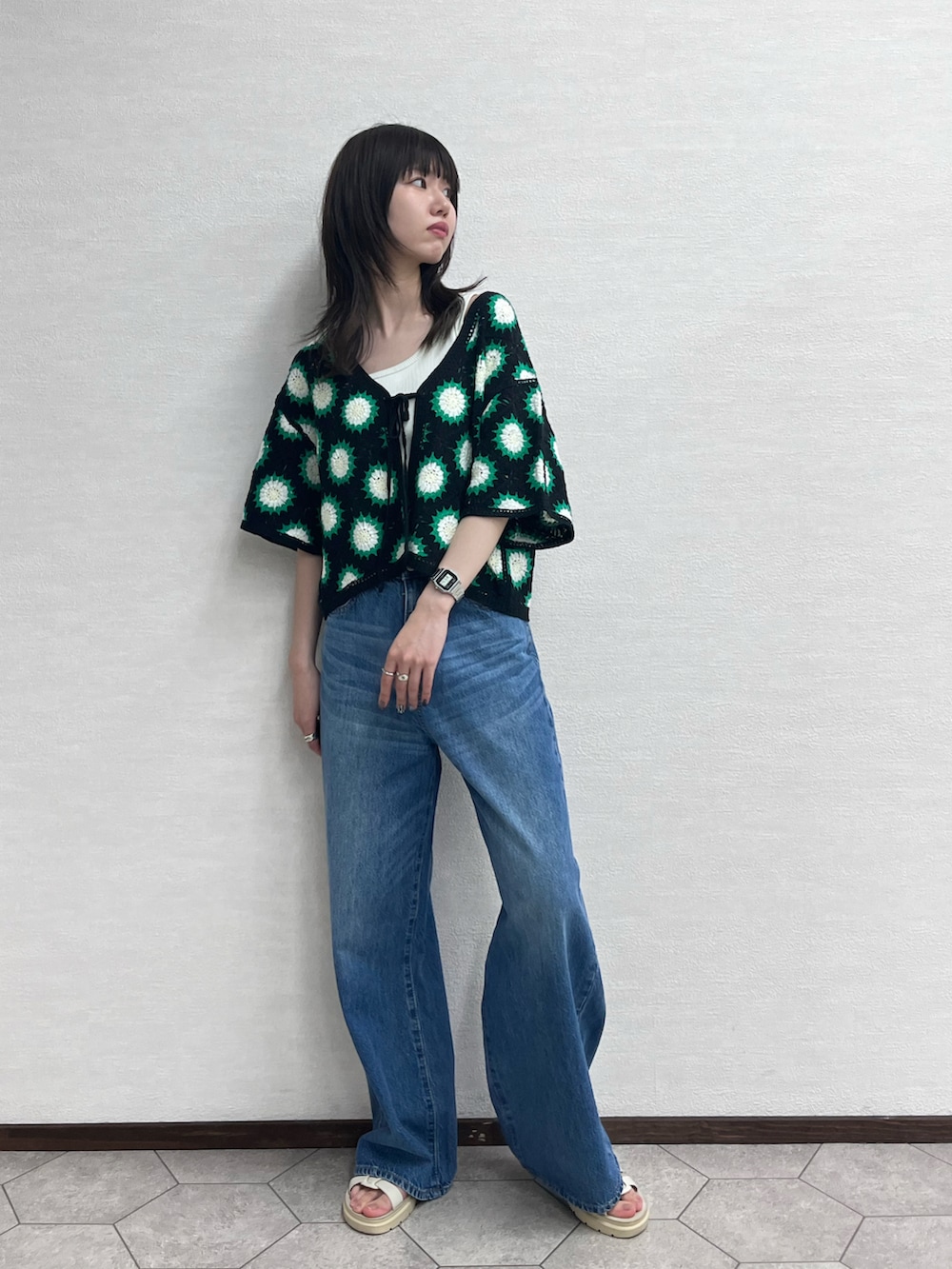 ブラック系のカーディガン/ボレロ、ブルー系のデニムパンツ、ホワイト系のシューズを着用したレディースの春コーディネートの2枚目の写真