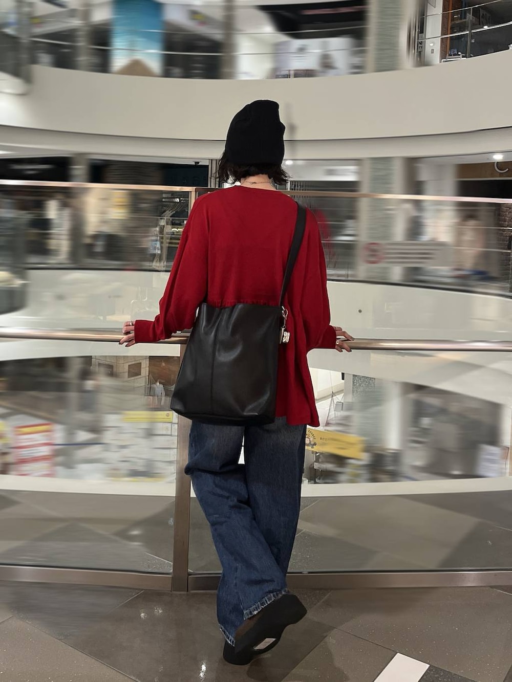 ブルー系のデニムパンツ、ブラウン系のサンダル、ブラック系のショルダーバッグを着用したレディースの秋コーディネートの3枚目の写真