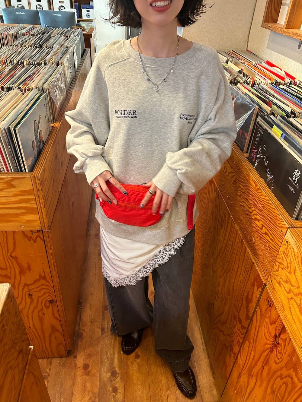 ブラック系のデニムパンツ、レッド系のボディバッグ/ウエストポーチ、グレー系のスウェットを着用したレディースの冬コーディネートの2枚目の写真