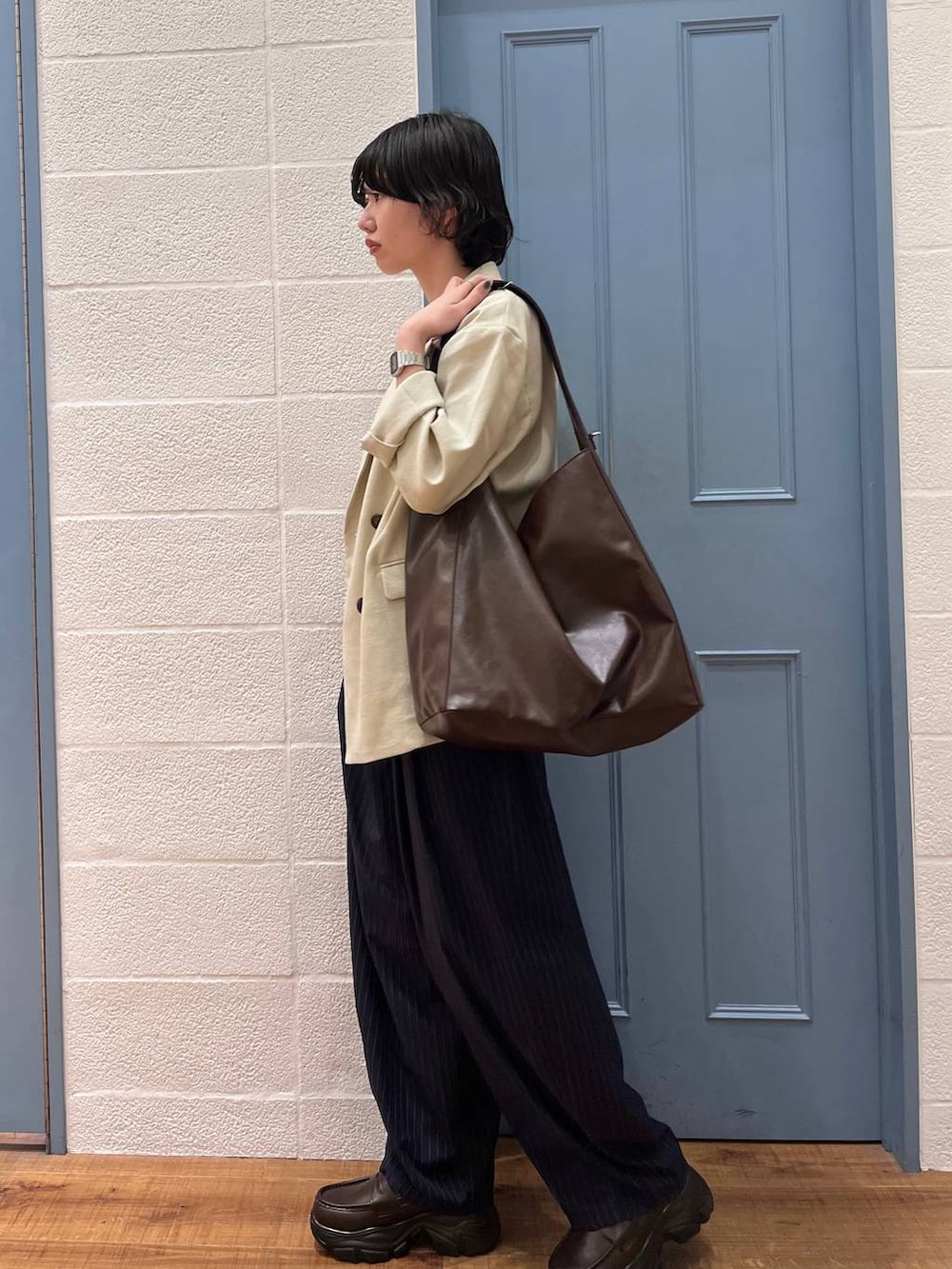 ブルー系のその他パンツ、ベージュ系のその他アウター、ブラウン系のショルダーバッグを着用したレディースの春コーディネートの2枚目の写真