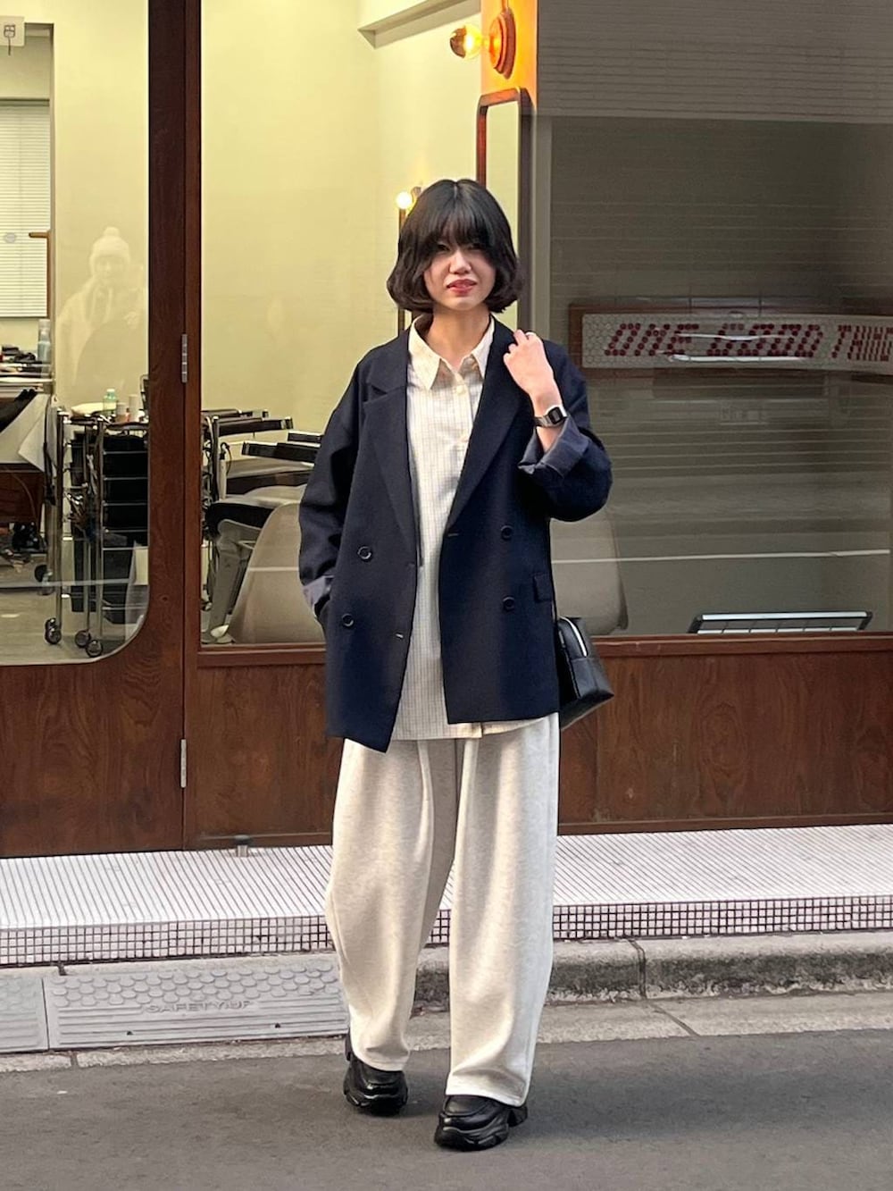 グレー系のスウェットパンツ、ブルー系のテーラードジャケット、ブラック系のローファーを着用したレディースの冬コーディネートの3枚目の写真