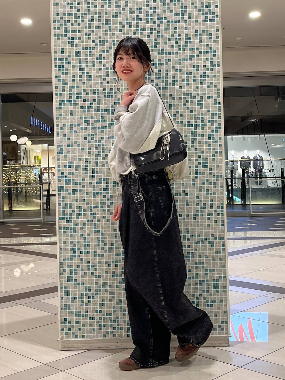 ブラック系のデニムパンツ、ブラック系のトートバッグ、グレー系のスウェットを着用したレディースの春コーディネートの3枚目の写真