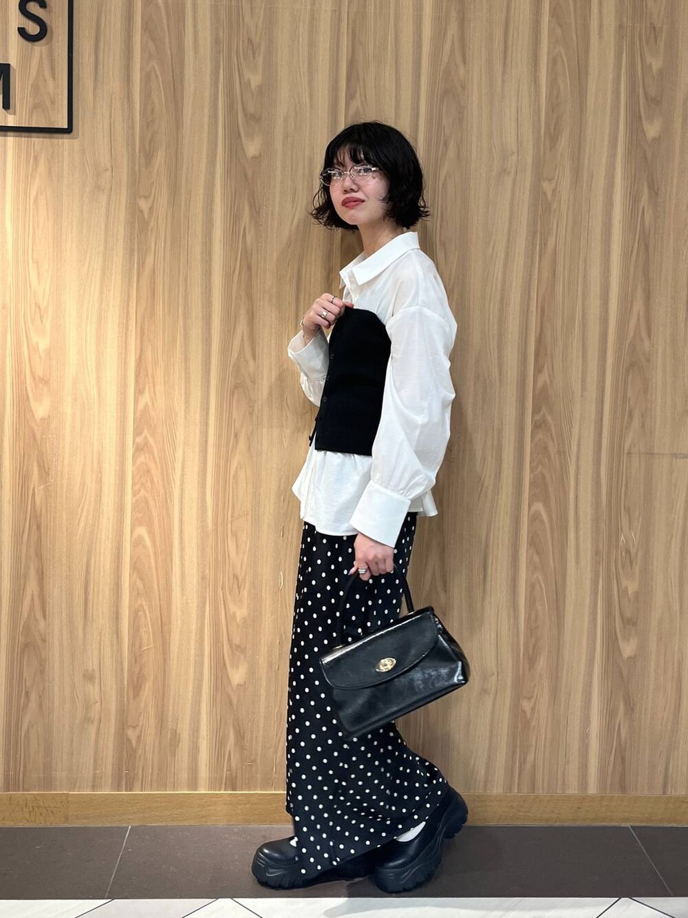 ブラック系のスニーカー、ブラック系のスカート、ブラック系のボストンバッグを着用したレディースの秋コーディネートの2枚目の写真