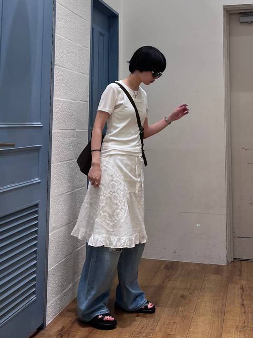 ブラック系のショルダーバッグ、ホワイト系のTシャツ/カットソー、ブルー系のデニムパンツを着用したレディースの夏コーディネートの2枚目の写真