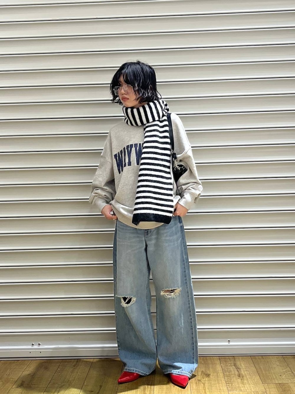 レッド系のパンプス、ブルー系のデニムパンツ、グレー系のスウェットを着用したレディースの冬コーディネートの3枚目の写真