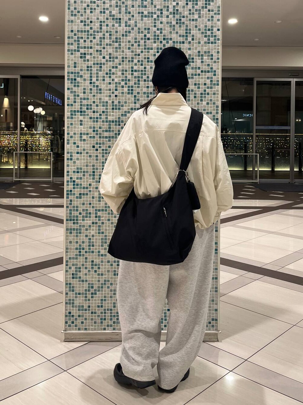 ブラウン系のショルダーバッグ、グレー系のスウェットパンツ、ホワイト系のナイロンジャケットを着用したレディースの冬コーディネートの3枚目の写真