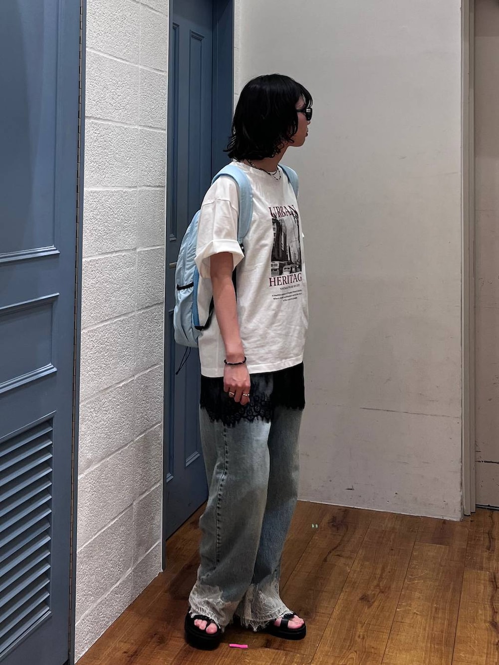ブルー系のデニムパンツ、ブラック系のサンダル、ブラック系のTシャツ/カットソーを着用したレディースの夏コーディネートの2枚目の写真