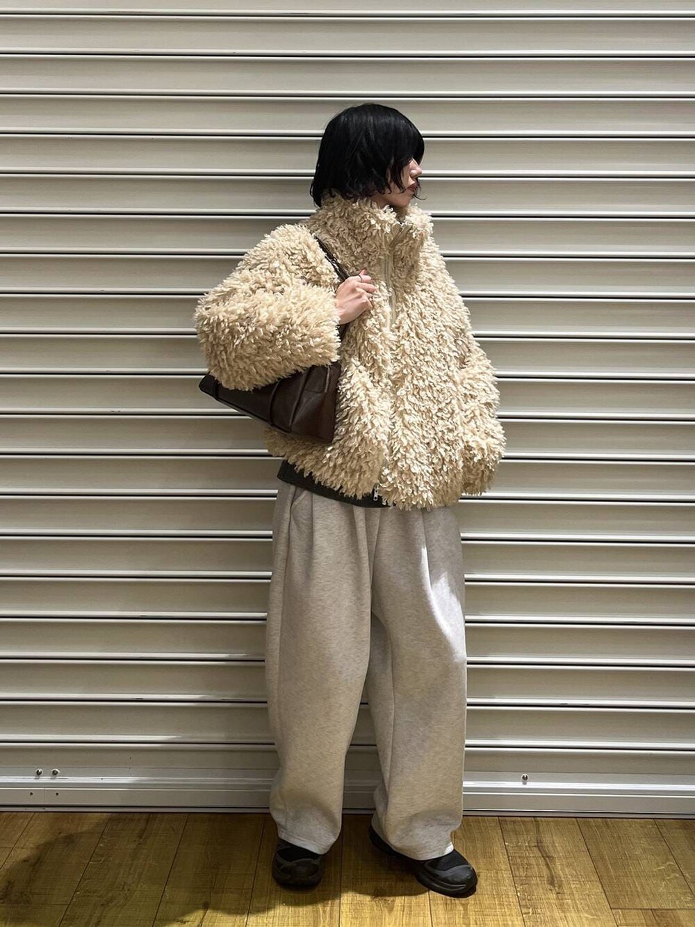 グレー系のスウェットパンツ、ブラウン系のボストンバッグ、ホワイト系のブルゾンを着用したレディースの冬コーディネートの2枚目の写真