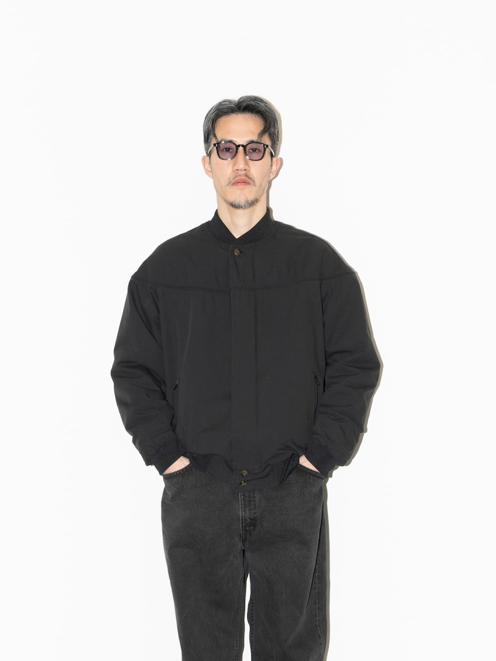 ブラック系のジャケット/アウター、オレンジ系のニット/セーター、ブラック系のデニムパンツを着用したメンズの冬コーディネートの2枚目の写真