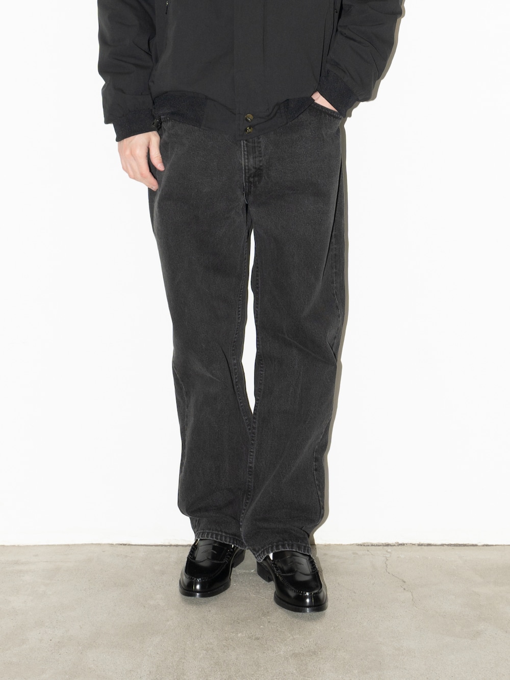 ブラック系のジャケット/アウター、オレンジ系のニット/セーター、ブラック系のデニムパンツを着用したメンズの冬コーディネートの3枚目の写真