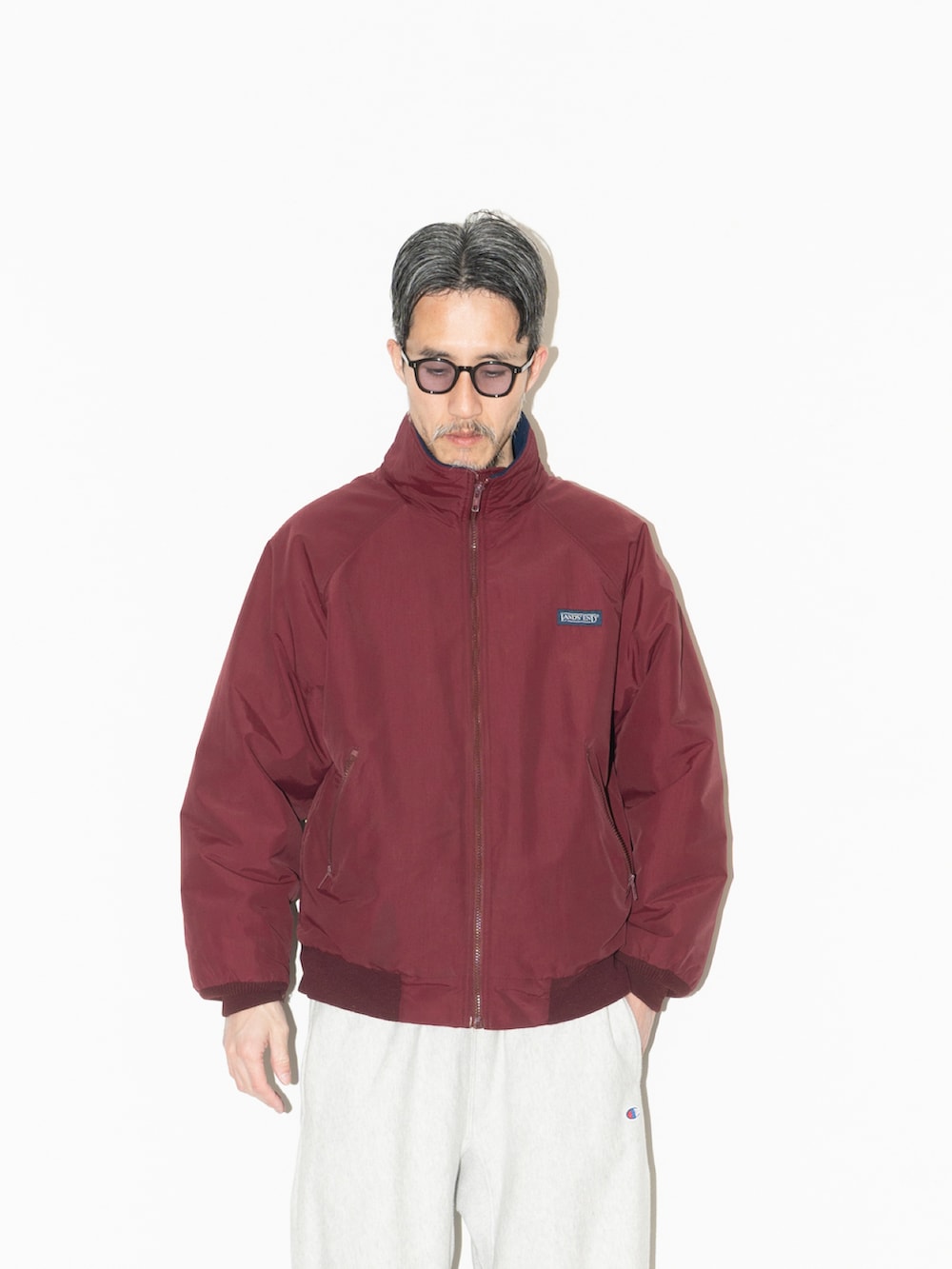 レッド系のジャケット/アウター、グレー系のパンツ、その他のシューズを着用したメンズの冬コーディネートの2枚目の写真