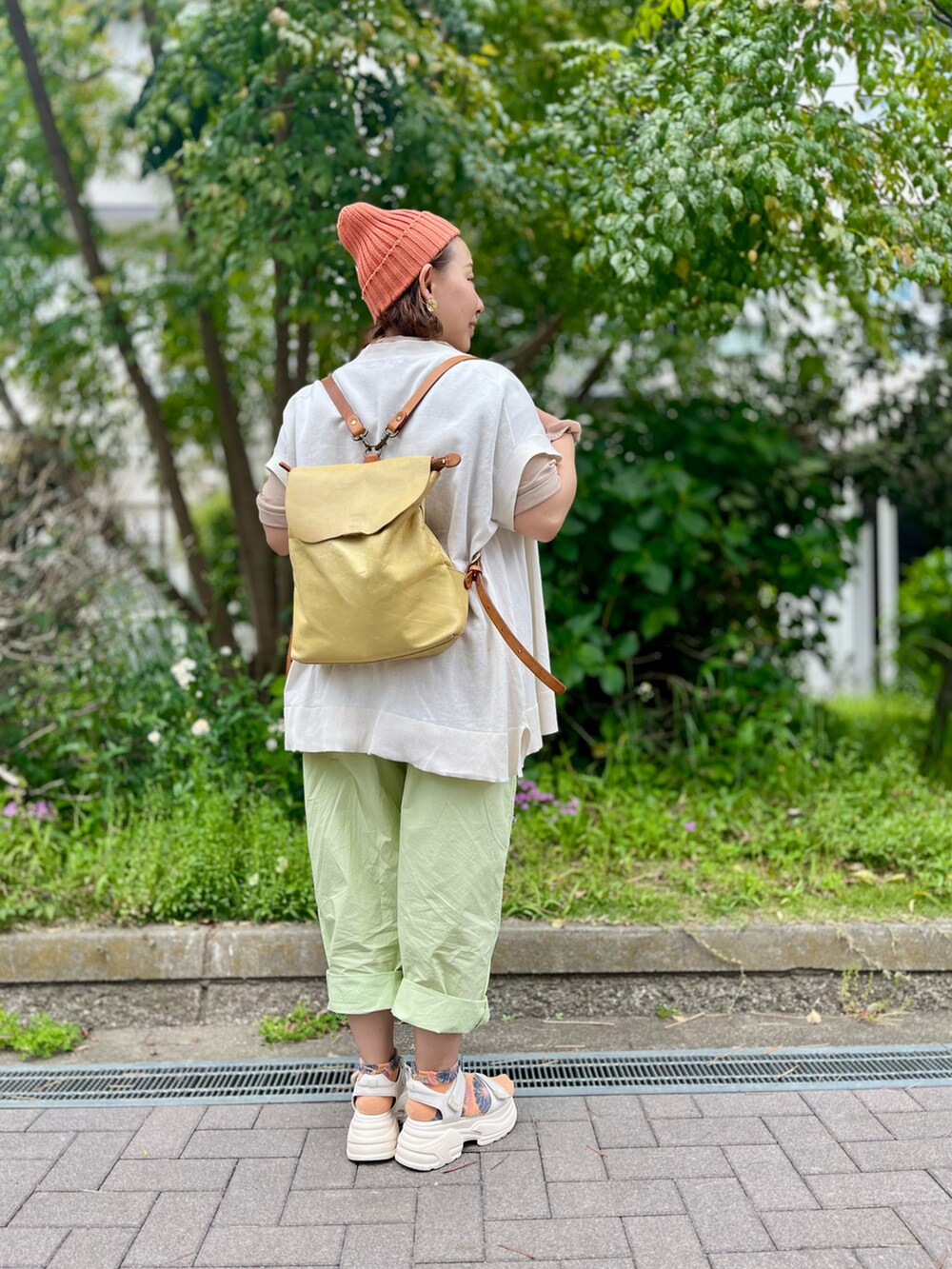 イエロー系のその他パンツ、イエロー系のバックパック/リュック、ベージュ系のTシャツ/カットソーを着用したレディースの春コーディネートの3枚目の写真