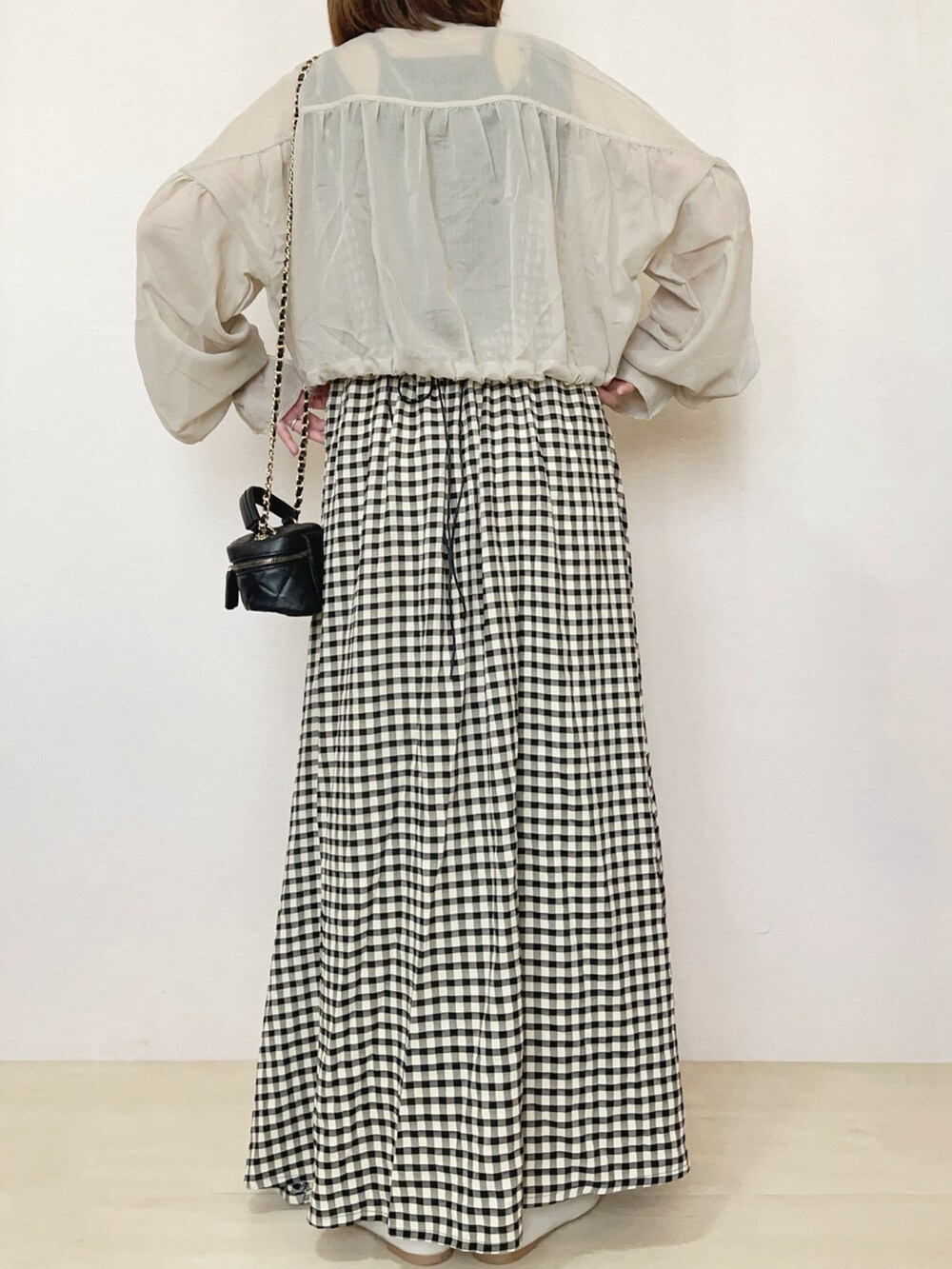 ベージュ系のブルゾン、ブラック系のワンピースを着用したレディースの春コーディネートの4枚目の写真