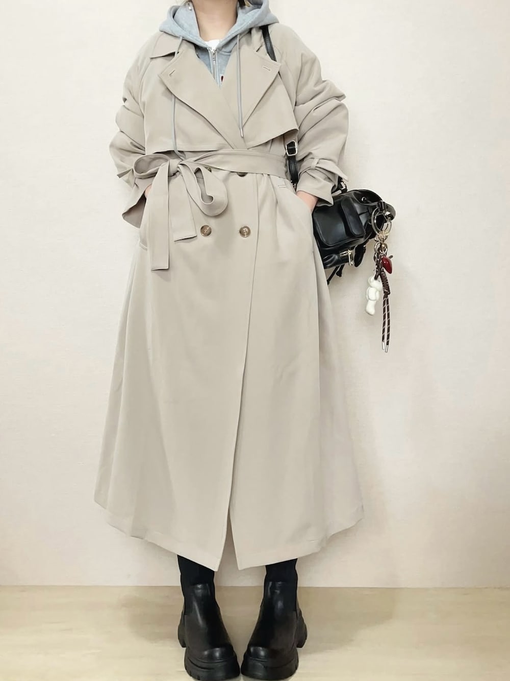 ベージュ系のトレンチコート、グレー系のパーカー、ブラック系のブーツを着用したレディースの冬コーディネートの5枚目の写真