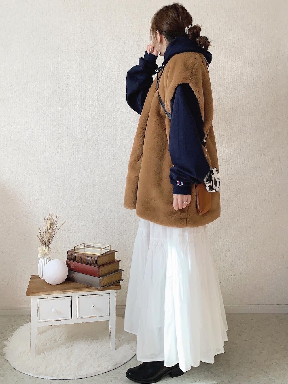 ブルー系のパーカー、ブラウン系のベスト、ホワイト系のスカートを着用したレディースの冬コーディネートの2枚目の写真