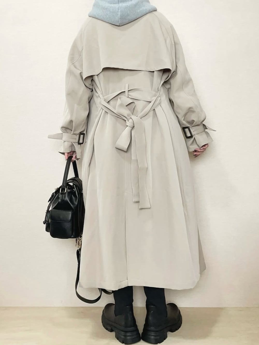 ベージュ系のトレンチコート、グレー系のパーカー、ブラック系のブーツを着用したレディースの冬コーディネートの4枚目の写真