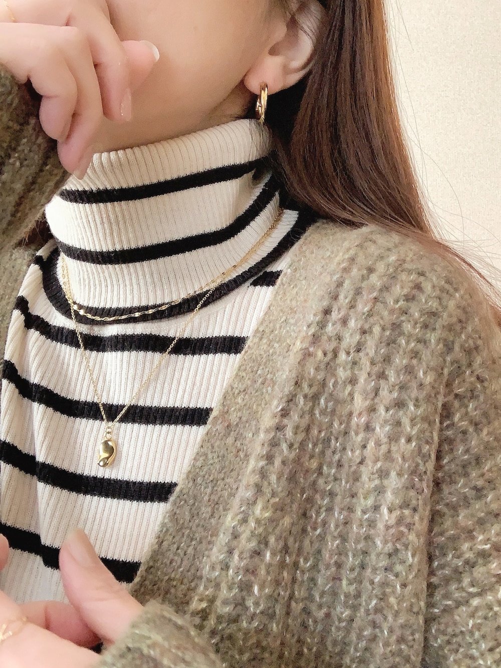 ゴールド系のピアス（両耳用）、ゴールド系のネックレス、ゴールド系のネックレスを着用したレディースの冬コーディネートの3枚目の写真